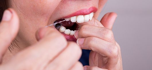 image of woman flossing teeth