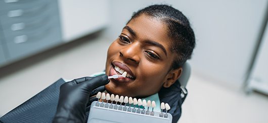 Dentist choosing the shade of teeth on patient